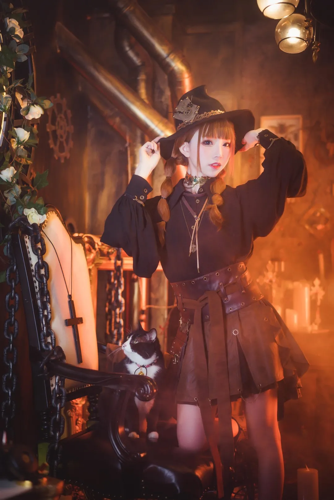 绮太郎_Kitaro棕色双辫戴黑色魔女帽，穿深色服饰站在暖色室内场景中