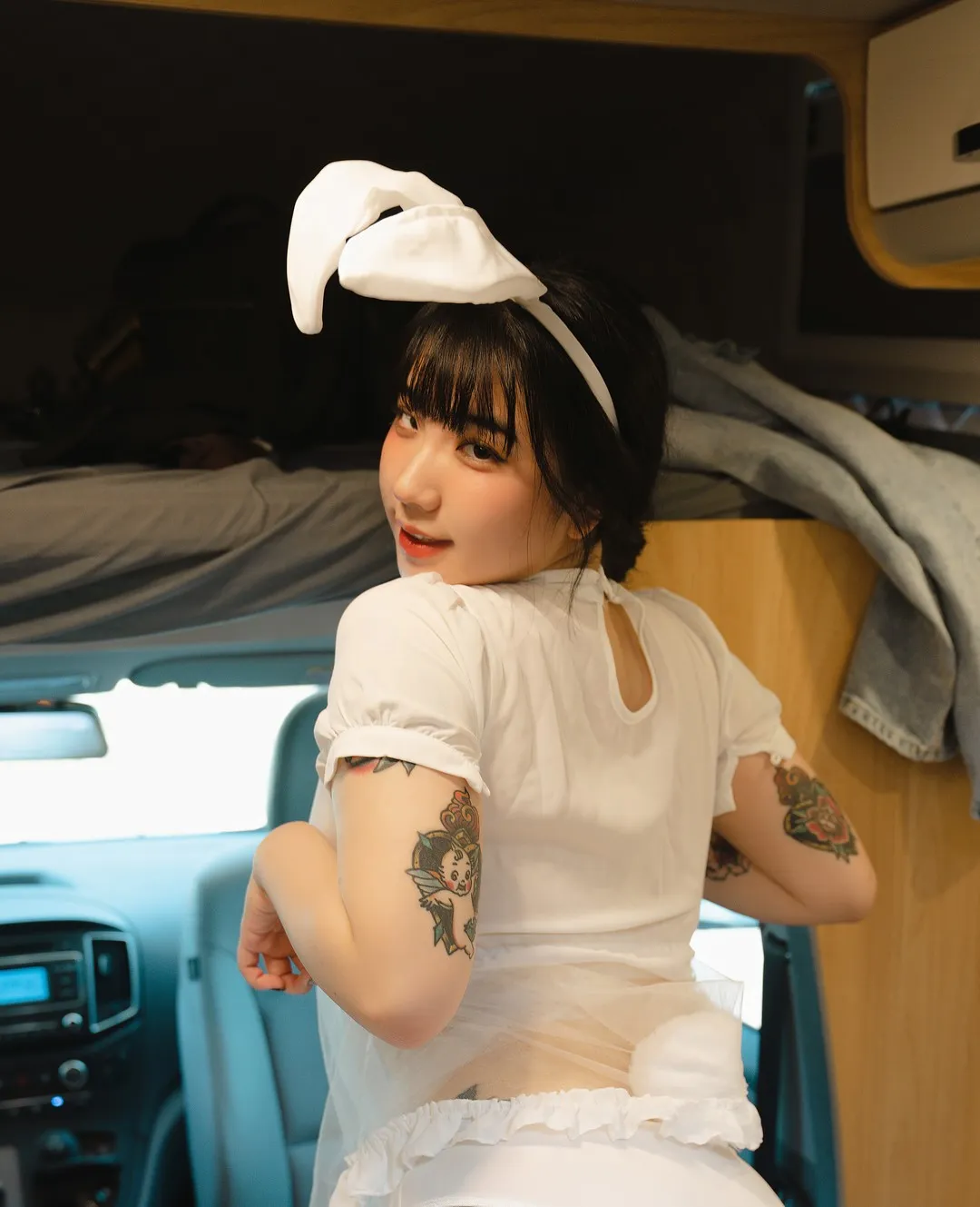 EchiH佩戴白色兔耳头饰身穿白色服装,位于车内空间中,展现主题造型自拍