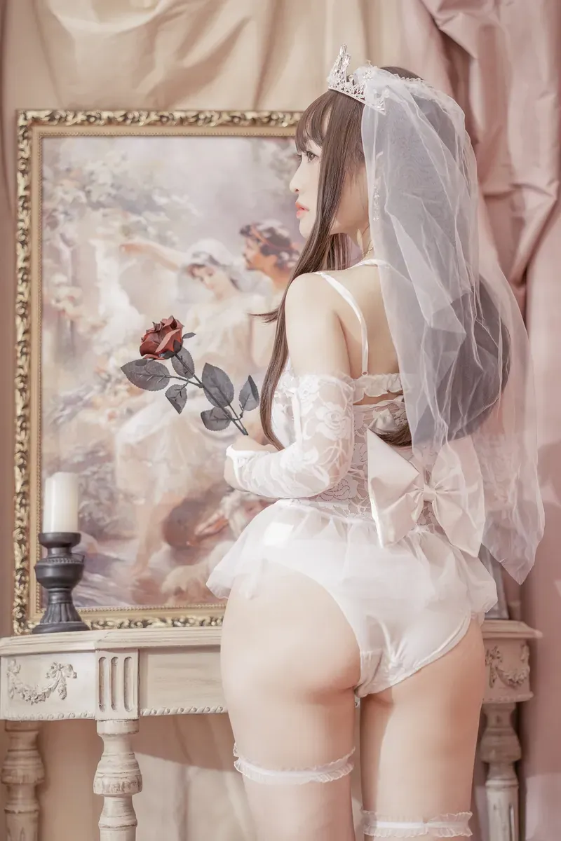 脱尾巴Mizuki白色婚纱头纱造型，手持玫瑰站在复古画框和烛台旁。