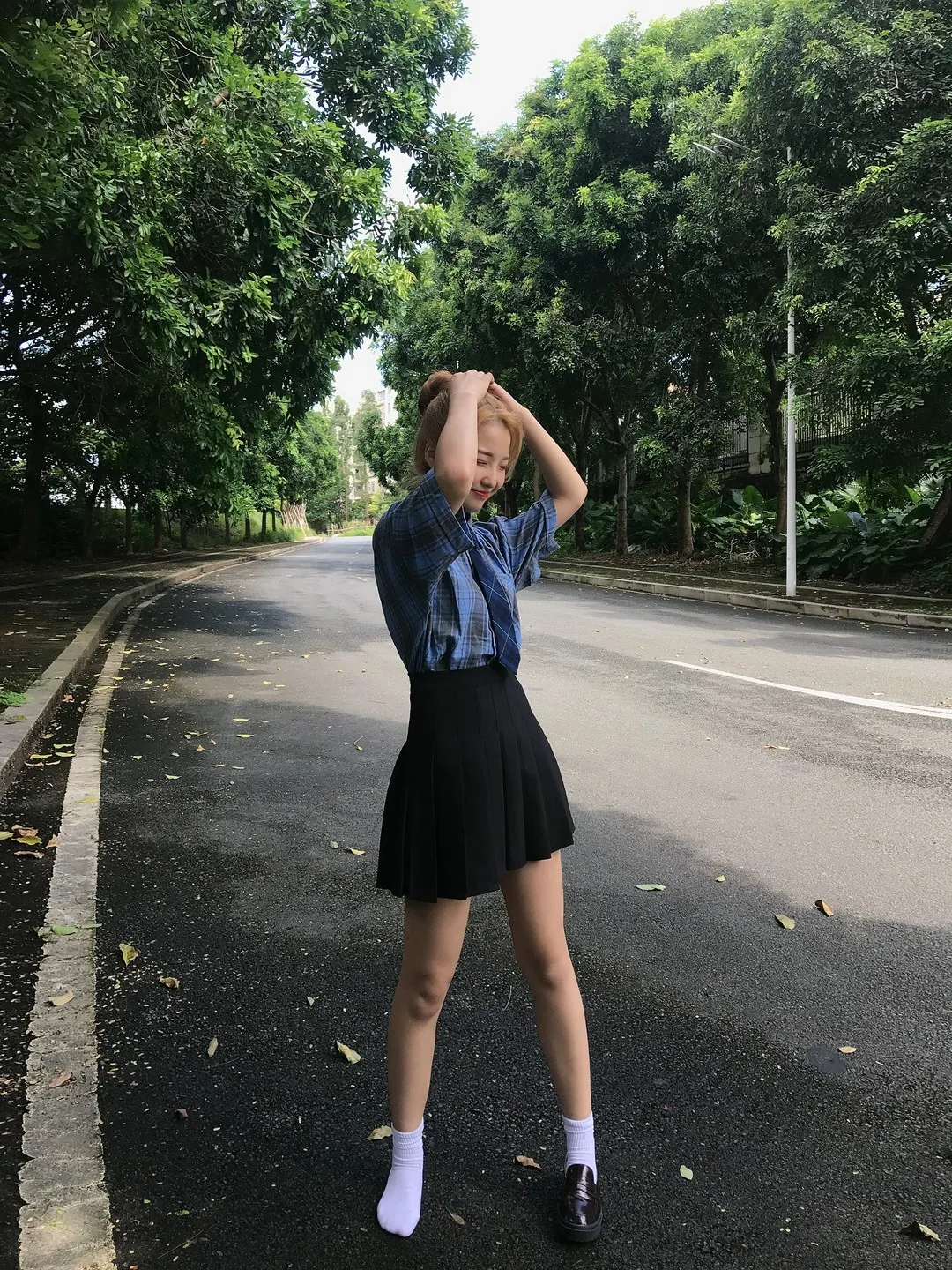 最爱帆布鞋 女性穿蓝色衬衫站在户外道路上的照片