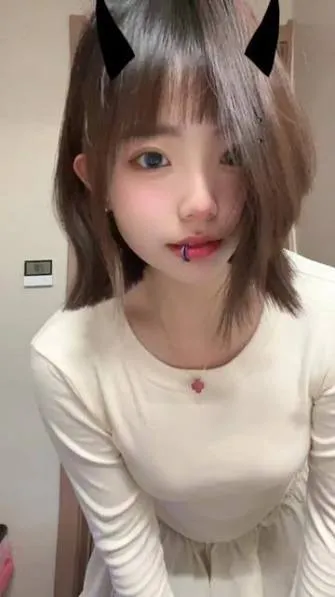 绘子sama白色服装近距离照片，人物佩戴头饰，背景为室内墙面。