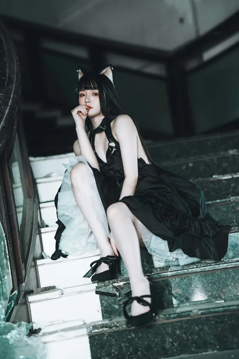 落落Raku黑色猫系服装坐姿照片，人物位于阶梯空间，黑色裙装与浅色皮肤形成视觉对比。