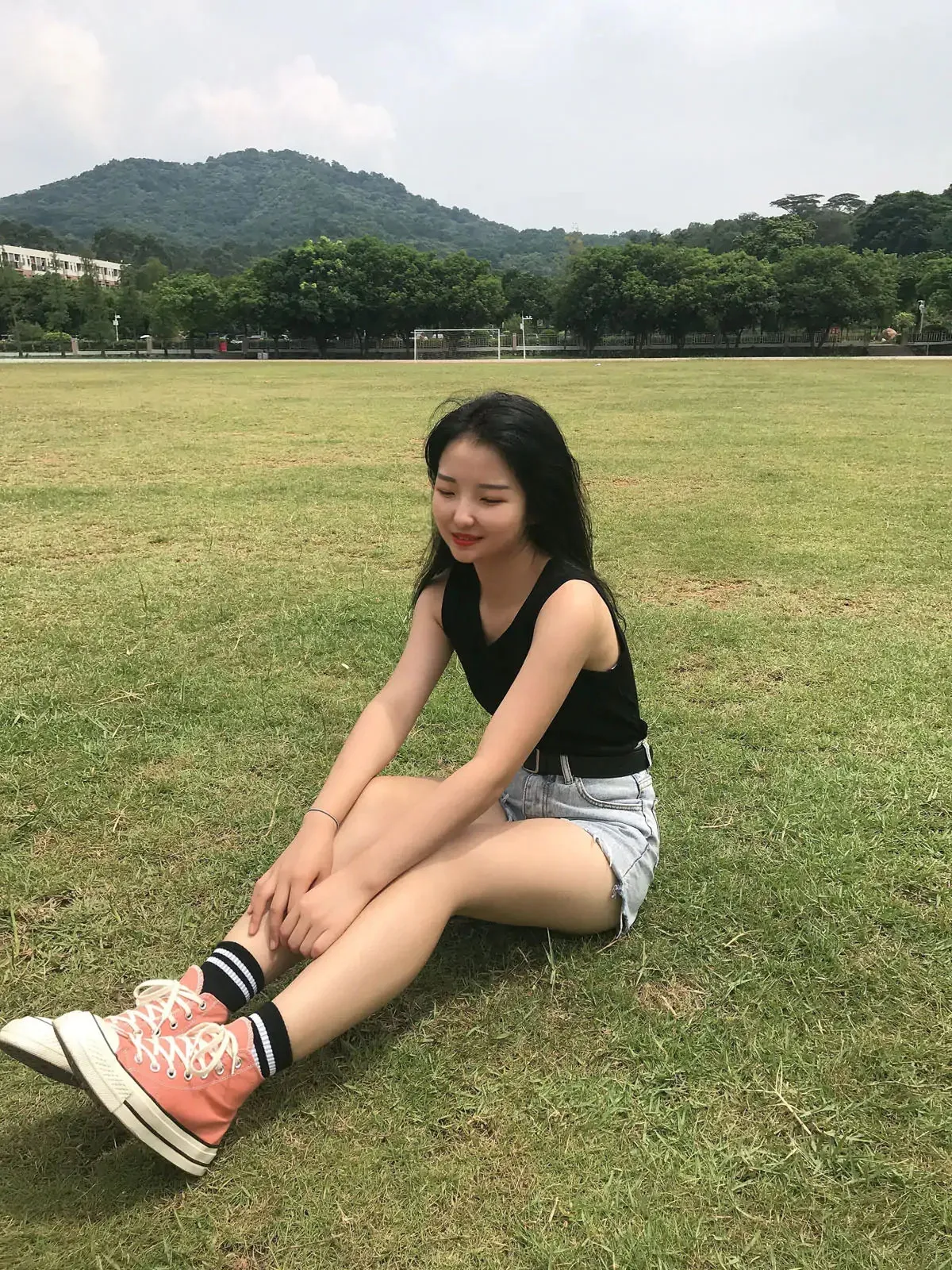 最爱帆布鞋 女性穿黑色上衣坐在草坪上的照片