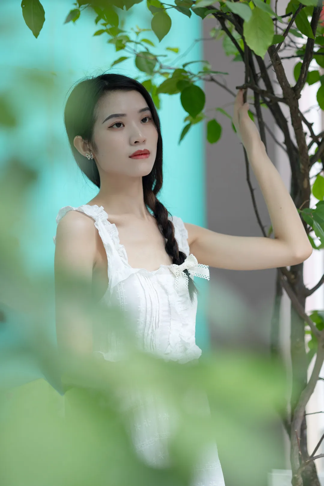 尤蜜丝 人物站在树旁并抬手触碰枝叶的照片