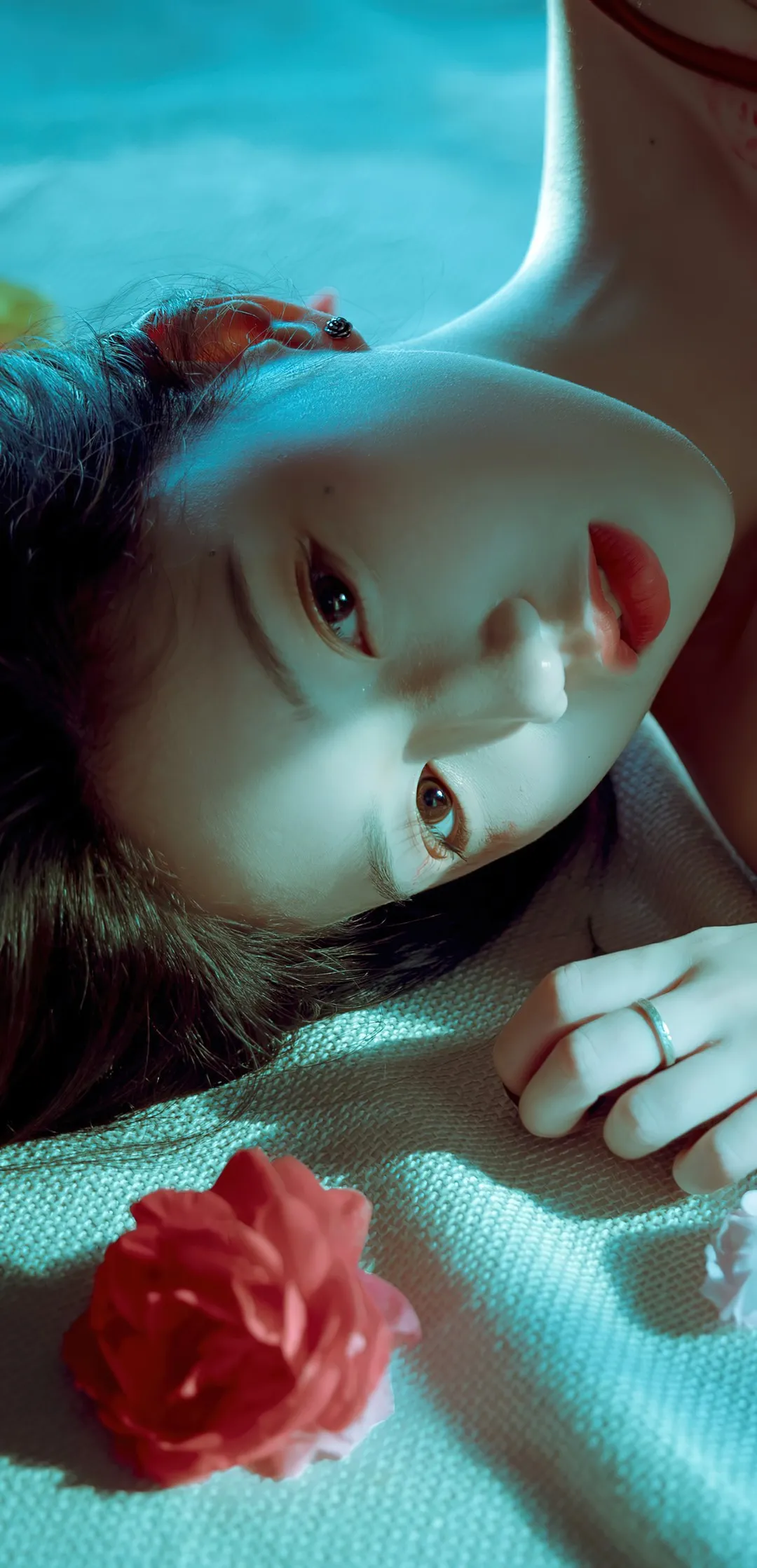 清池相关人像照片，人物侧躺在织物表面，带有蓝绿色光线效果