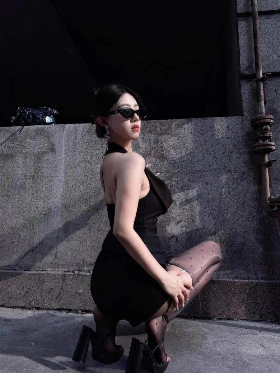 抖音小野马 户外墙面前穿黑色服装的坐姿照片