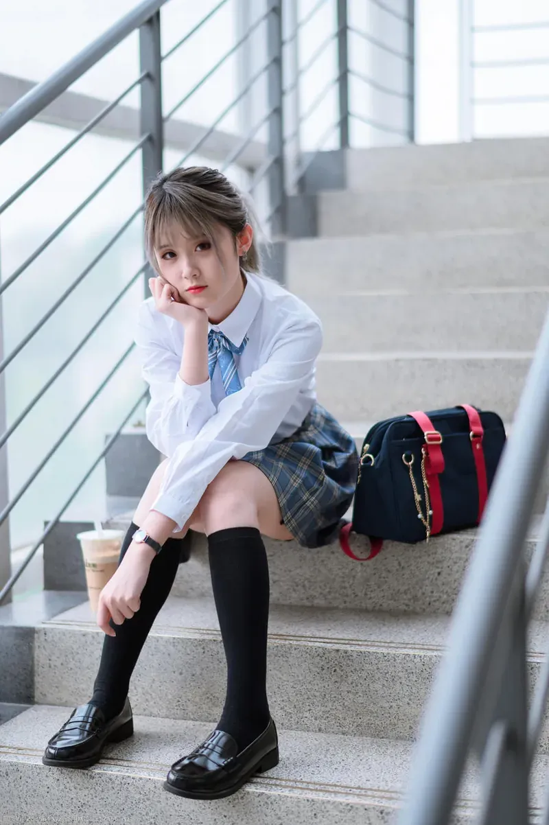 程程程穿白色衬衫和格纹裙装坐在楼梯区域的写真照片