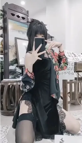 御女茉莉身着黑色蕾丝旗袍与花卉开衫跪坐在铺满书法纸张的室内地毯上